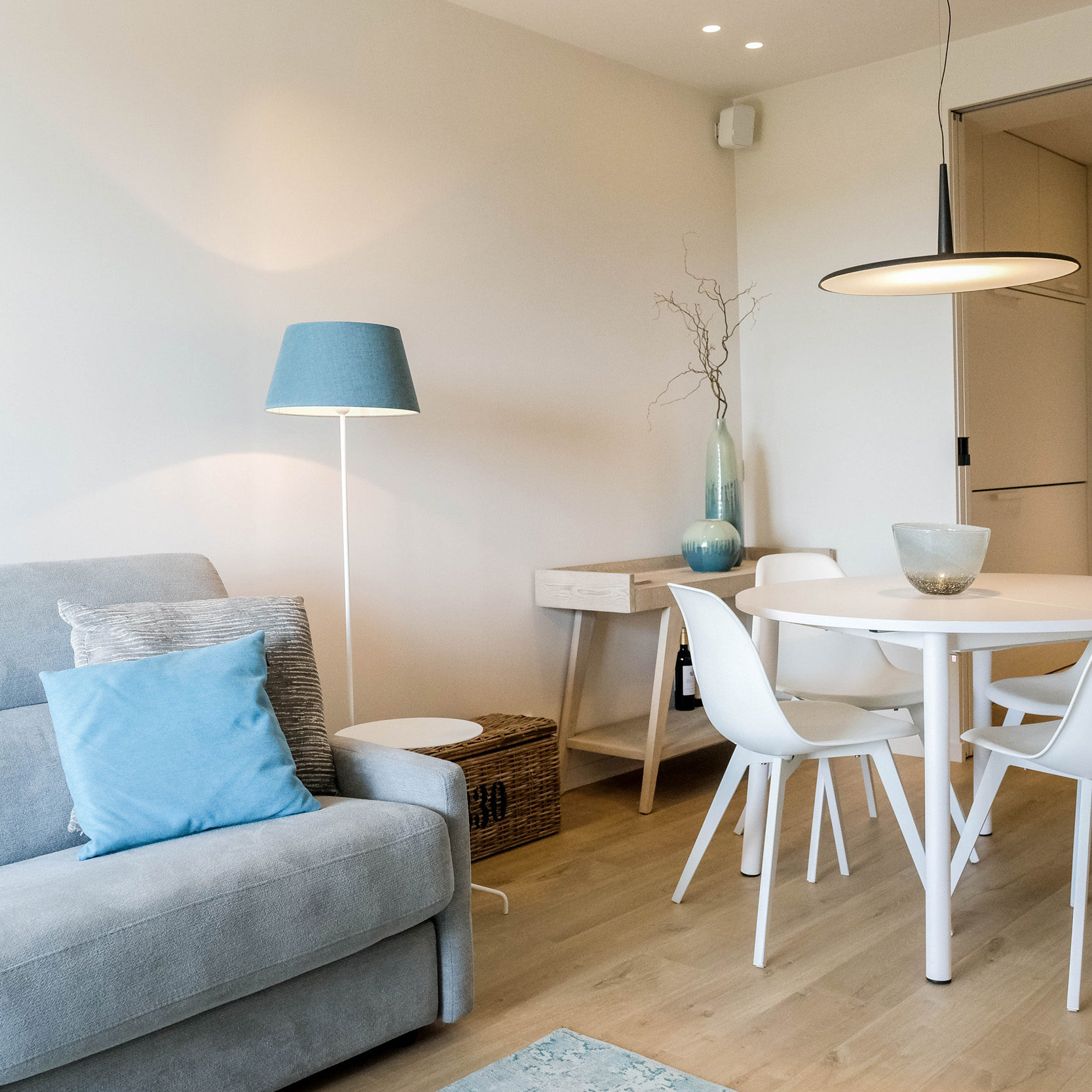 Moderne woonkamer in gezellig appartement met grijze zetel houten vloer en witte tafel